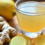 3 Ingredient Brazilian Mounjaro: The Viral Wellness Drink You Can Make at Home 6 A glass of golden ginger lemon detox drink with fresh ginger slices and a lemon on a wooden table.