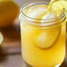 Brazilian Mounjaro drink with lemon slice and ice cubes in a mason jar.