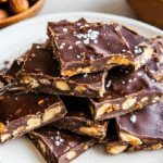 Date Bark: The Best Sweet Treat Trend You Need to Try Today 7 Date bark slices with chocolate, peanuts, and sea salt on a white plate.