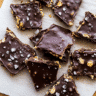 Top view of chocolate date bark squares with sea salt and peanuts on parchment paper.