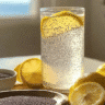Glass of bariatric seed tonic with lemon slices and chia seeds with fresh lemons and chia bowl.