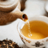 Close-up of Japanese Green Tea Hojicha being poured from a teapot into a white Japanese tea cup.
