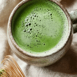 What Is the Japanese Mounjaro Recipe? Uncover Japan's Secret Drink for Natural Weight Loss 5 A rustic mug of frothy Japanese green tea beside a bamboo whisk on a soft beige cloth.