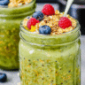 Mason jars of matcha overnight oats topped with blueberries, raspberries, granola, and honey drizzle.