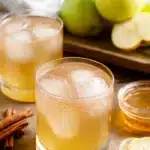 Apple Cider Vinegar for Weight Loss Recipe: The Complete Guide 5 A refreshing glass of apple cider vinegar for weight loss recipe with ice cubes, cinnamon sticks, fresh apples, lemon slices, and honey on a wooden table.