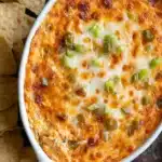 Buffalo Chicken Dip fresh from the oven with melted cheese and green onions, served with tortilla chips.