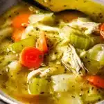 A bowl of cabbage chicken soup for weight loss with carrots, celery, and shredded chicken in a light golden broth, served in a rustic dish.