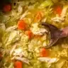 A pot of cabbage chicken soup for weight loss filled with tender chicken, cabbage, carrots, and celery in a golden broth.