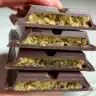 Close-up view of Trader Joe's Dubai chocolate bars stacked together, showing a pistachio-filled layer inside rich dark chocolate.