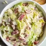 Viral Iceberg Lettuce Salad: The Fresh Trend Everyone’s Talking About 5 Close-up of a creamy iceberg lettuce salad with salami, onions, cheese, and dressing served in a white bowl.