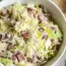 Bowl of viral iceberg lettuce salad with onions, cheese, and deli meats in a creamy dressing.