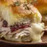 Close-up of Thanksgiving leftover slider with turkey, cranberry sauce, and melted cheese on a buttery brioche roll.