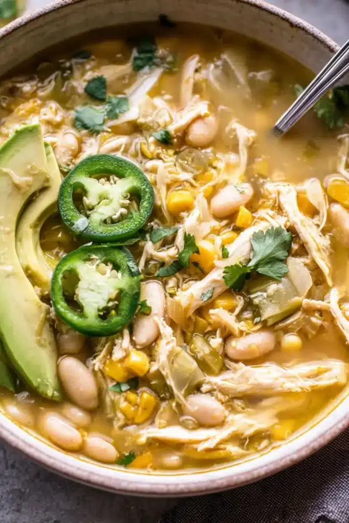 A warm, hearty bowl of Southwest White Chicken Chili made with tender shredded chicken, white beans, corn, and a hint of spice — topped with avocado, jalapeños, and cilantro for the perfect cozy meal.