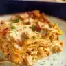 Slice of Thanksgiving leftovers lasagna served on a plate with golden melted cheese and visible layers of turkey and pasta.