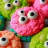 Close-up of colorful Halloween Eyeball cookies decorated with candy eyeballs in bright pink, green, orange, and blue.