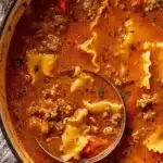 Overhead view of a pot of high protein lasagna soup with lasagna noodles, ground meat, tomato broth, and a ladle.