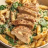 Creamy Garlic Parmesan Chicken Pasta with sliced seared chicken, penne, spinach, and Parmesan served in a white bowl.