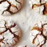 Gingerbread crinkle cookies coated in powdered sugar and arranged on parchment paper.