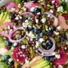 Colorful spring salad with blueberries, pistachios, watermelon radish, avocado, feta, and pink berry dressing.