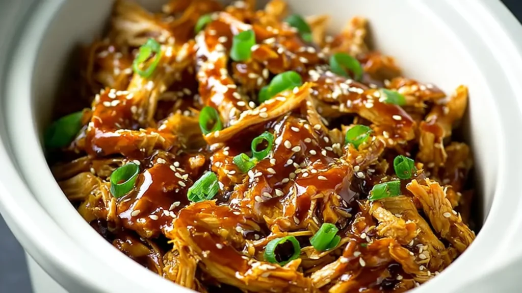 Dump and Go Crockpot Teriyaki Chicken Easy Slow Cooker Dinner for Busy Days 5 Tender shredded teriyaki chicken in a slow cooker topped with sesame seeds and green onions.