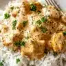 Creamy smothered chicken served over white rice and topped with fresh parsley.