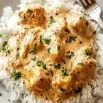 Tender chicken smothered in a rich, creamy seasoned sauce, served over fluffy rice for the ultimate comfort meal.