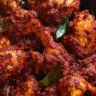 Close-up of authentic Chicken Ghee Roast with deep red roasted masala coating tender chicken pieces and curry leaves.