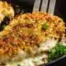 Parmesan-crusted chicken breast with a golden, crispy topping in a cast iron skillet.